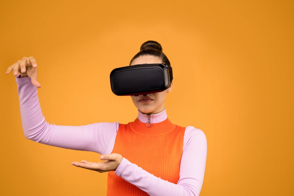 Imagen de una mujer joven utilizando unas gafas de realidad virtual realizando movimientos con las manos fruto de su experiencia virtual.