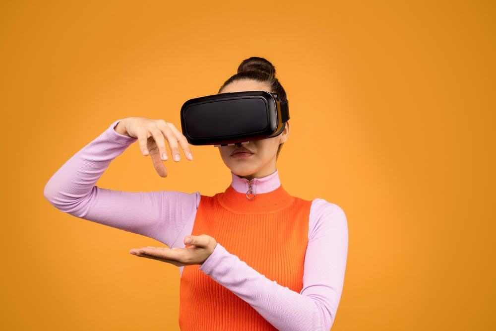 Imagen de una mujer joven utilizando unas gafas de realidad virtual realizando movimientos con las manos fruto de su experiencia virtual.