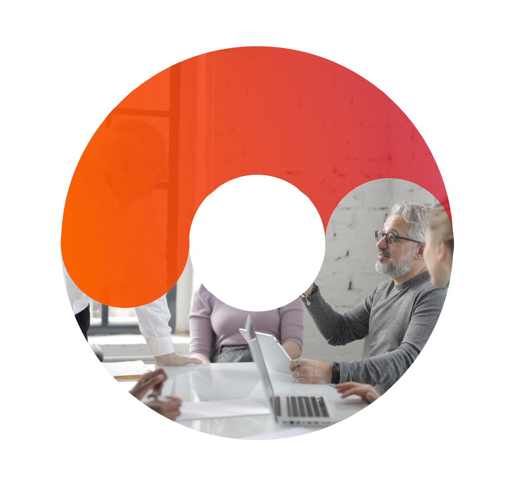 Creatividad realizada con forma circular, segmentada por un degradado naranja, en cuya imagen principal aparecen varias personas sentadas en alrededor de una mesa, charlando de manera distendida frente a la pantalla de un ordenador.